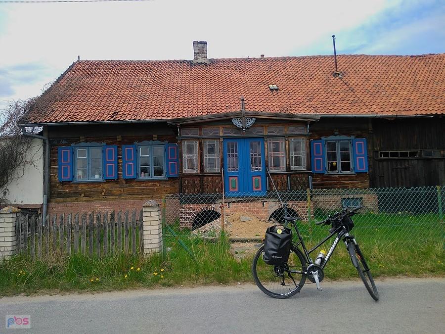 Dom z niebieskimi okiennicami i rowerem