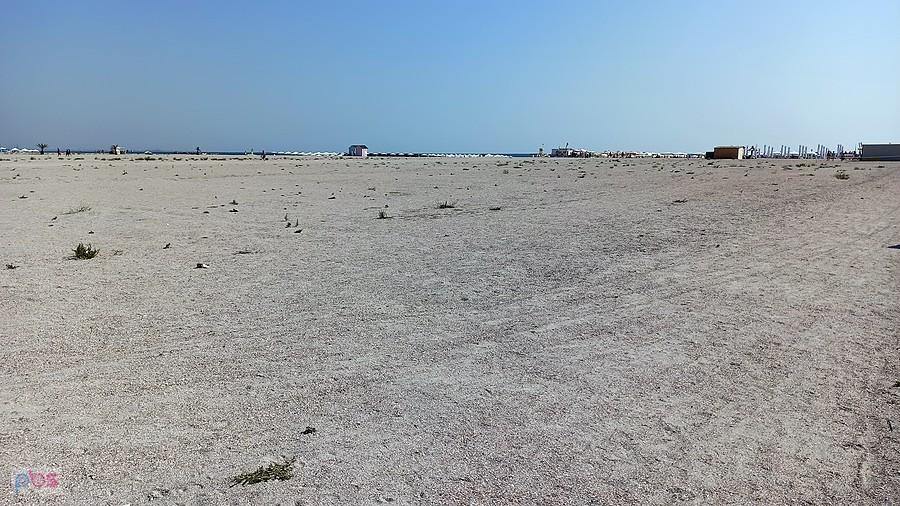 Plaża tak szeroka, że ledwo widać parasole nad brzegiem morza
