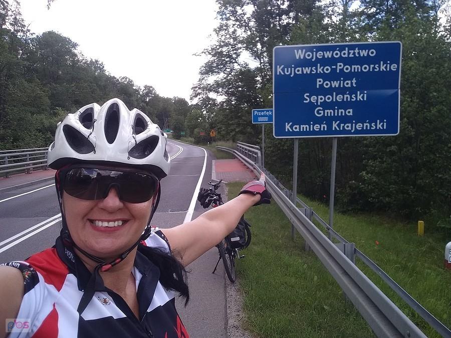 Rowerzystka przy znaku Gmina Kamień Krajeński