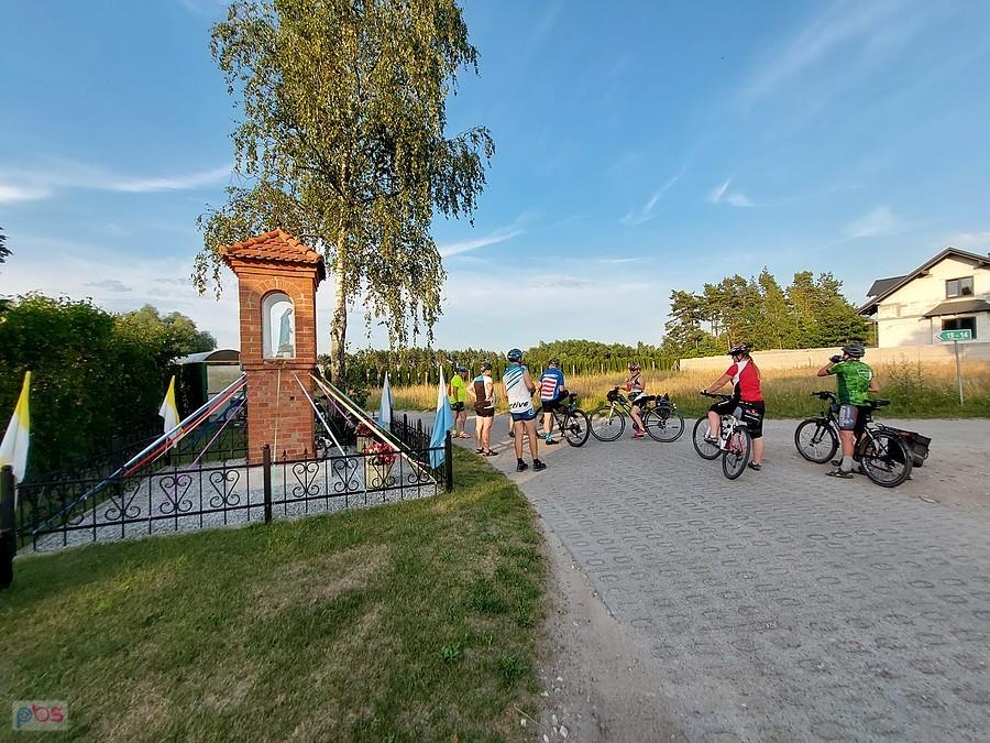 Grupa rowerzystów przy kapliczce na wsi