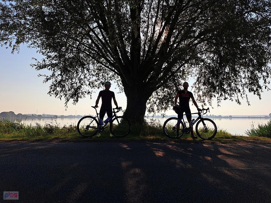 Dwóch rowerzystów pod drzewem nad jeziorem