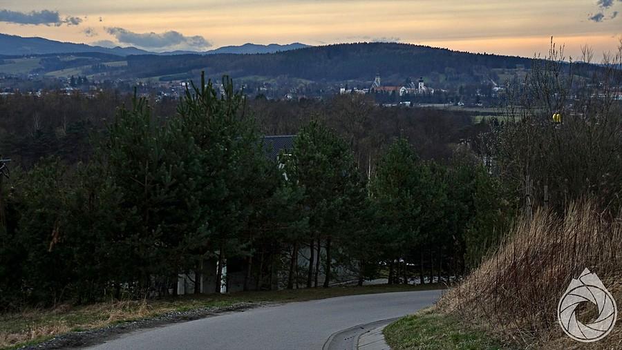 zjazd w stronę Starego Sącza, z kompleksem klasztornym i Gorcami w tle
