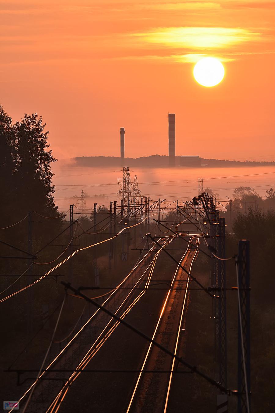 Wschód słońca nad linią kolejową D29-61 w Częstochowie. Na horyzoncie kominy huty szkła "Guardian".