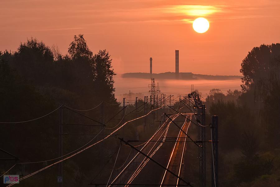 Wschód słońca nad linią kolejową D29-61 w Częstochowie. Na horyzoncie kominy huty szkła "Guardian".