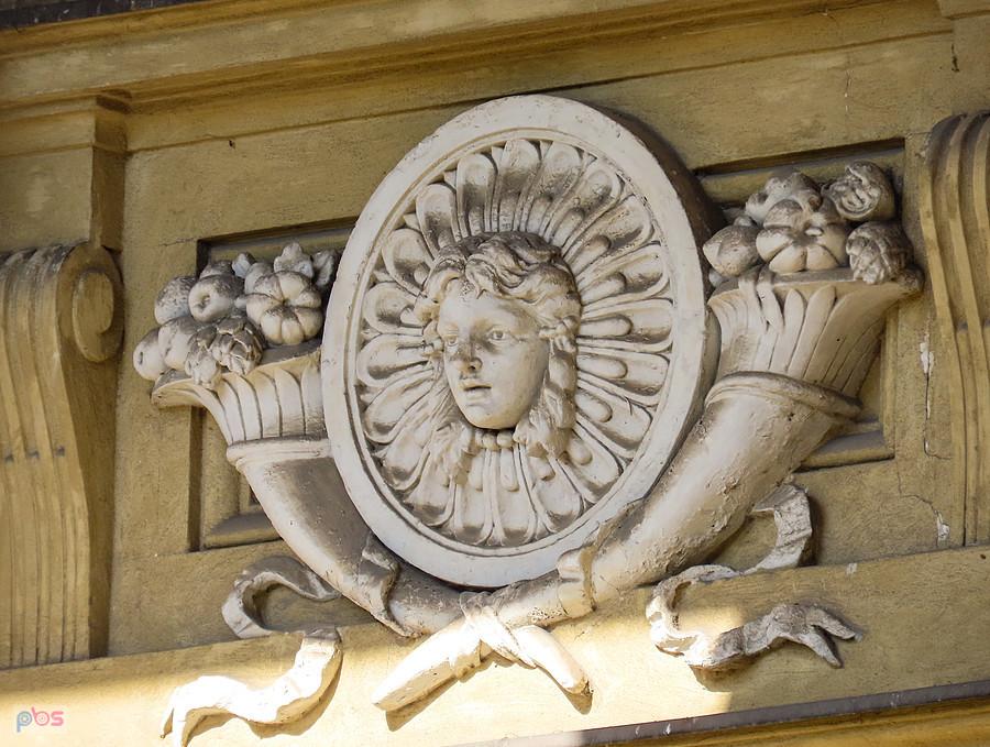 Zakurzony medalion młodej kobiety otoczony rogami obfitości