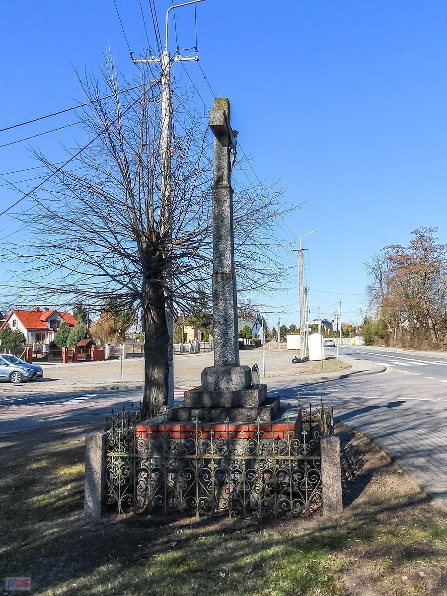 Kamienny krzyż przy kościele z oryginalnym żeliwnym ogrodzeniem