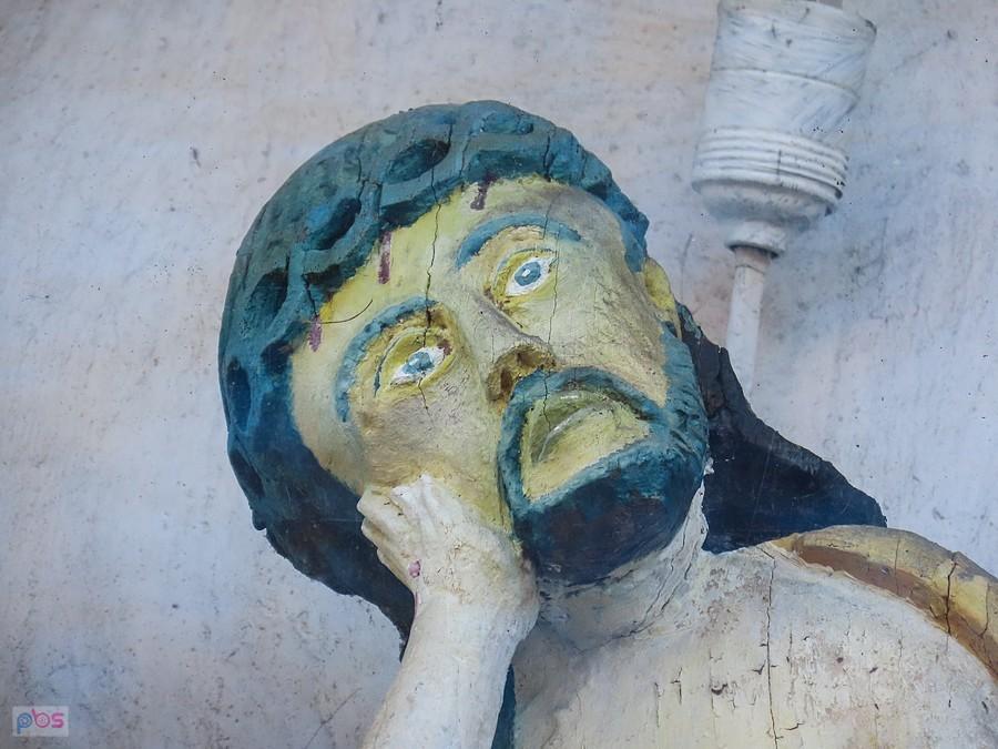 Chrystus Frasobliwy zamknięty za szybką w murze kościelnym